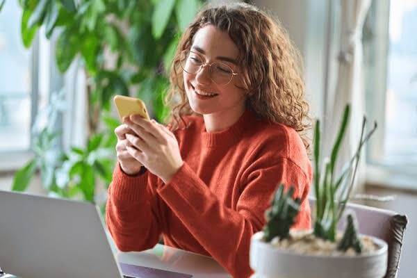 Una donna guarda il suo telefono con un sorriso sul viso