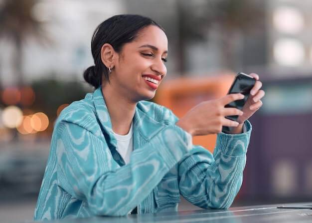 Woman smiles when she sees text message expressing deep gratitude and appreciation on her phone