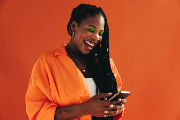 A woman smiling while reading a text message on her mobile phone