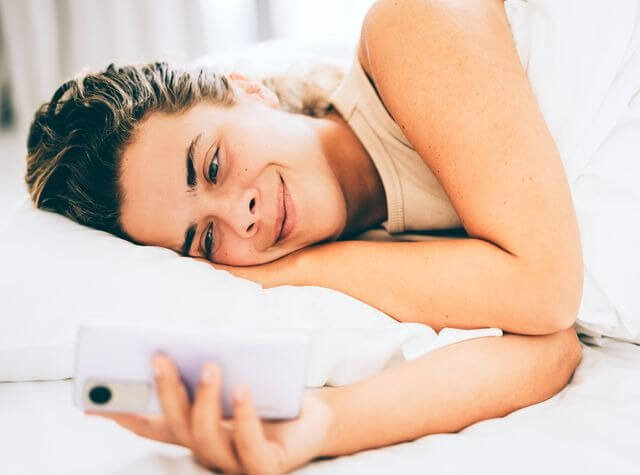 a girl is smiling and looking at her phone