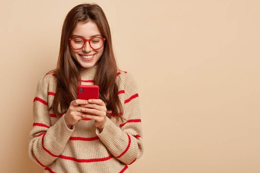 a teenage girl texts on cellular, reads interesting article online