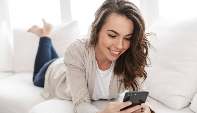 a woman is lying in the bed while playing on her phone